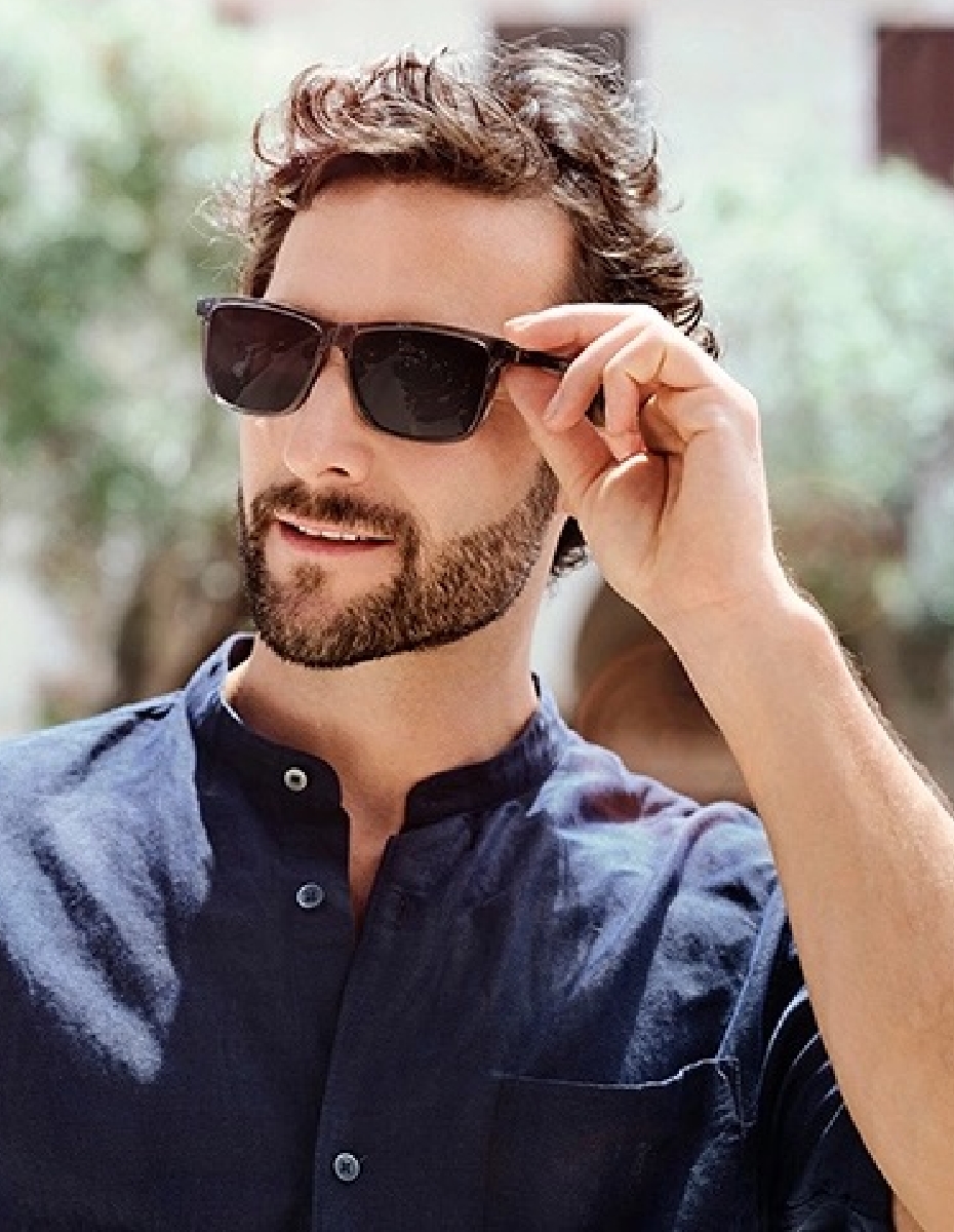 Mann sitzt in der Sonne und trägt Sonnenbrille.